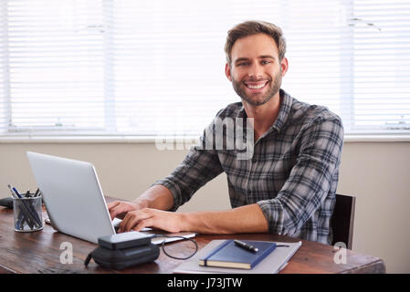Young male student smiling at camera while working on assignment Stock Photo