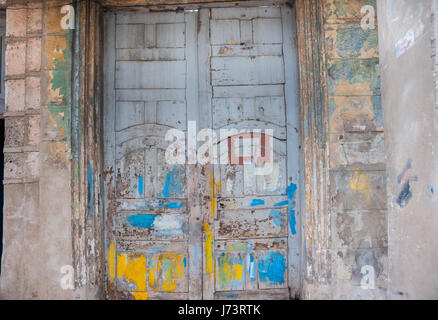 Double closed door seen best of days, daubed in paint, cracked, peeling  weathered and uncared, for in need of repairs and maintenance in Havana, Cuba Stock Photo