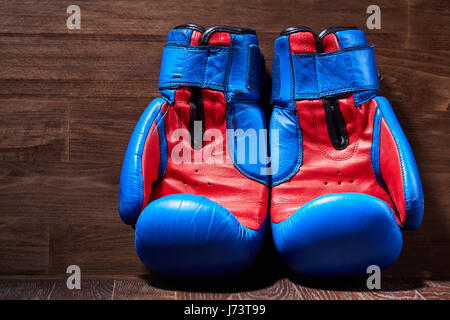 Close-up of the pair of red and blue boxing gloves on the wooden plank. Stock Photo
