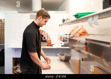 chef preparing pizza dough in kitchen at pizzeria Stock Photo