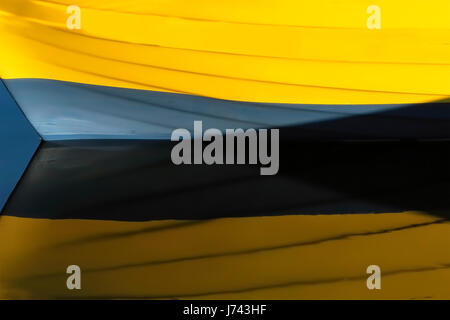 Detail of an anchored boat reflected in the calm sea water close the edge of the pier. Stock Photo