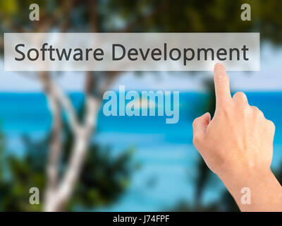 Software Development - Hand pressing a button on blurred background concept . Business, technology, internet concept. Stock Photo Stock Photo