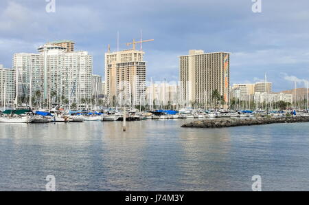 Honolulu, Hawaii, USA - May 30, 2016: Yachts docked at Ala Wai Boat Harbor in the Kahanamoku Lagoon against cityscape of Ala Moana. Stock Photo