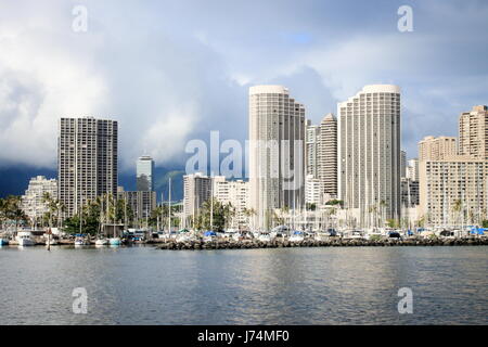 Honolulu, Hawaii, USA - May 30, 2016: Yachts docked at Ala Wai Boat Harbor in the Kahanamoku Lagoon against cityscape of Ala Moana. Stock Photo