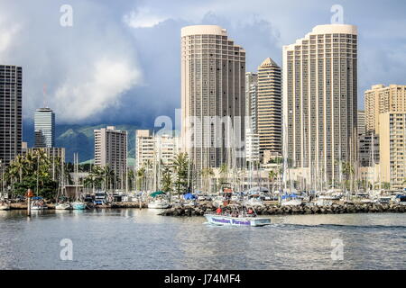Honolulu, Hawaii, USA - May 30, 2016: Yachts docked at Ala Wai Boat Harbor in the Kahanamoku Lagoon against cityscape of Ala Moana. Stock Photo