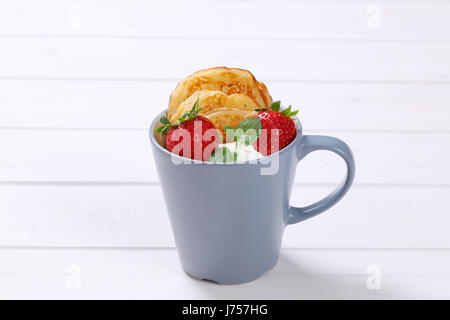 cup of american pancakes with white yogurt and fresh strawberries on white wooden background Stock Photo