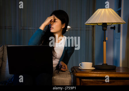 beautiful business girl having high intraocular pressure at night while working in free clothing at comfortable office massaging eyes relieving stress Stock Photo