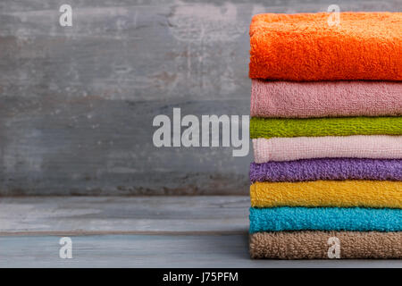 Stack of colorful bath towels over blue rustic background Stock Photo
