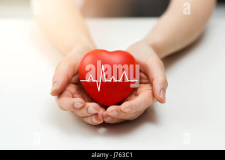 cardiology or health insurance concept - red heart in hands