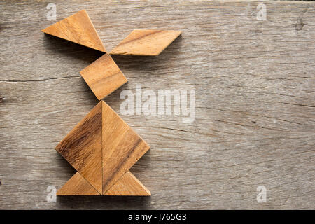 Chinese tangram puzzle in rabbit shape on wooden background (Concept for easter) Stock Photo