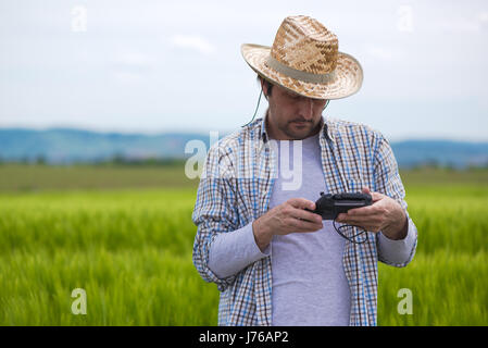 Smart farming concept, farmer using drone remote controller to navigate aircraft in cultivated field and examine crops Stock Photo