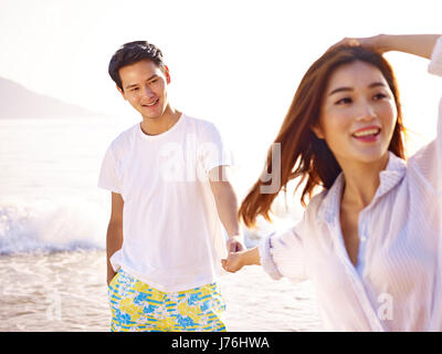 young loving and happy asian couple holding hands on beach. Stock Photo