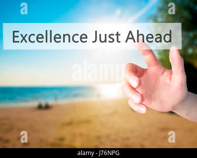 Excellence Just Ahead - Hand pressing a button on blurred background concept . Business, technology, internet concept. Stock Photo Stock Photo