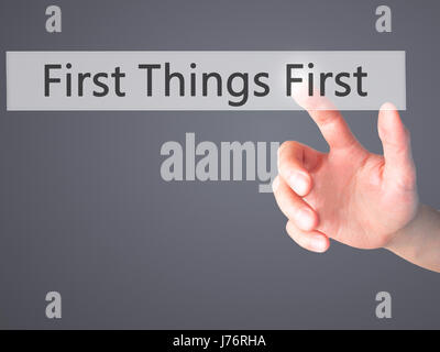 First Things First - Hand pressing a button on blurred background ...