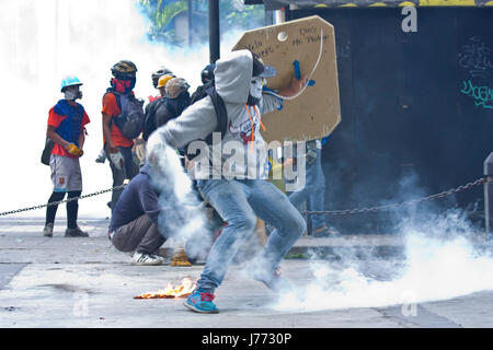 A demonstrator throws back to the police a tear gas canister during a protest against the government of Nicolas Maduro in Caracas. Stock Photo