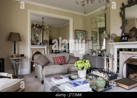 Drawing room with ottoman, chandelier and three-seater linen sofa all from Bardoe & Appel. The walls are painted in Oxford Stone estate by Farrow & Ba Stock Photo