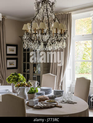 Elaborate chandelier and ornate table lamp both by Bardoe & Appel in dining room painted in Stone III flat emulsion by Paint Library Stock Photo