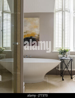 Napoli freestanding bath by Victoria & Albert in bathroom with painting by Susanne Winter and limestone floor tiles Stock Photo