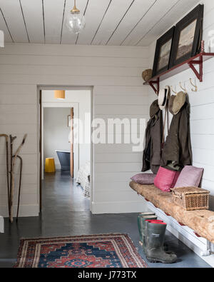 17th century stone cottage Jackets and hats hang in hallway of Stock Photo