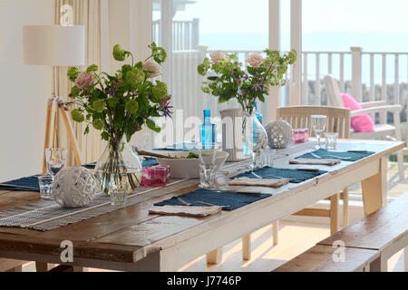 Lunch laid on wooden farm house table in kitchen diner with balcony views out to the sea Stock Photo