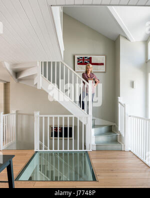 Glass floor on first storey landing with framed old british flags along the staircase. The walls are painted in Quill Grey by Sanderson. Stock Photo