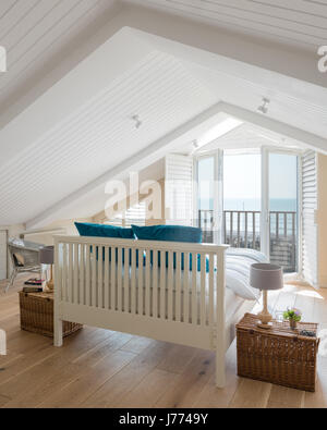Feather & Black bed in top floor master bedroom with pitched ceiling, balcony and shutters. Hampers from Fortnum & Mason have been used as bedside tab Stock Photo