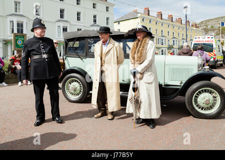 Llandudno, North Wales- 29th April 2017: People dressed in Victorian costume standing alongside a vintage citron car at Llandudno promenade as part of Stock Photo