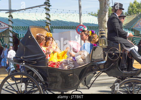 Seville, Spain - May 02, 2017:  People dressed in traditional costumes riding horse carriages and celebrating Seville's April Fair Stock Photo