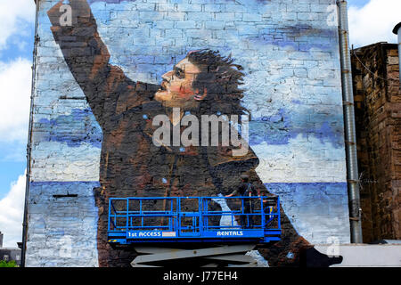 Glasgow, UK. 23rd May, 2017. 'Bob' the anonymous street artist, is putting the finishing touches to a 50 foot street mural of Billy Connolly, one of three, as part of Glasgow City's celebration of the world famous comedian's 75th birthday later this year. Billy is also being honoured by a tribute of portraits by Scottish artists John Byrne, Jack Vettriano and Racheal MacLean exhibiting in The Peoples Palace Museum in Glasgow Credit: Findlay/Alamy Live News Stock Photo