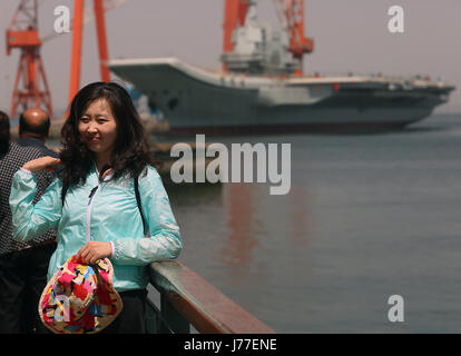 Dalian, LIAONING, CHINA. 6th May, 2017. Chinese pose for photos with China's first domestically built aircraft carrier, officially launched last month, parked in the shipyard where it was built in the port city Dalian, one of China's major ports, in Liaoning Province on May 6, 2017. The carrier is not ready for operation, but it was hailed as a naval milestone in President Xi Jinping's drive to extend China's military reach far beyond its shores. Credit: Stephen Shaver/ZUMA Wire/Alamy Live News Stock Photo