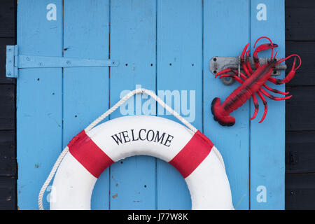 Welcome lifebelt and plastic lobster on a blue wooden shed door in a designed garden at a flower show. UK Stock Photo