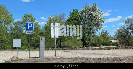 The paid parking is equipped near the village. There is no asphalt, only clay crushed stone and the earth. On a background spring the blossoming apple Stock Photo