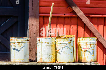 Brosarp, Sweden - May 18, 2017: Documentary of public historic railway station. Four old paint buckets standing on wooden planks outside a red buildin Stock Photo