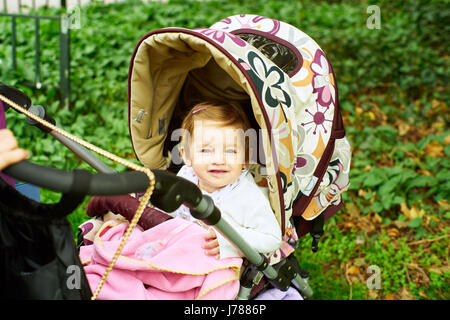 A baby sitting in a pram outdoors Stock Photo