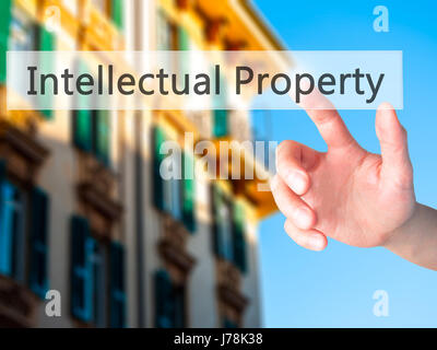 Intellectual Property - Hand pressing a button on blurred background concept . Business, technology, internet concept. Stock Photo Stock Photo