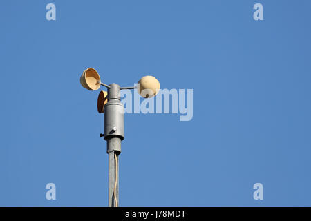 Anemometer measuring wind speed with small cups pushed by the wind like a small windmill against clear blue skies Stock Photo