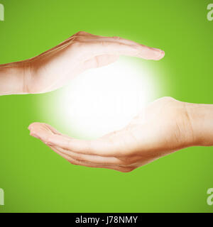 Two hands hold a glowing light or sun as symbol for meditation or pray Stock Photo