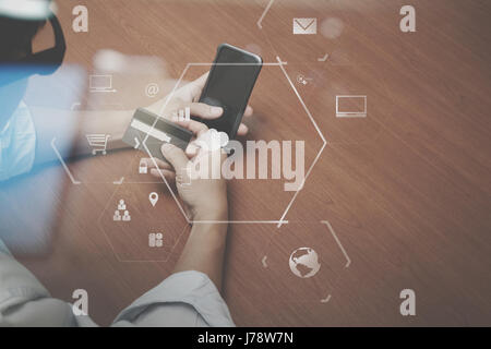 top view of Hand using credit card and mobile phone on wooden desk with VR icon chart graph diagram Stock Photo