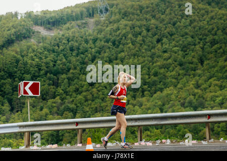 Rosa Khutor, Russia -  May 7, 2017: young woman runner on water point in hand sponge with water in race Spring mountain marathon Stock Photo