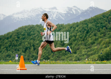 Rosa Khutor, Russia -  May 7, 2017: runner leader race runs in background of mountains and green forests in race Spring mountain marathon Stock Photo