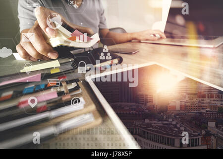 businessman working with laptop computer and document on wooden desk in modern office with virtual icons interface Stock Photo