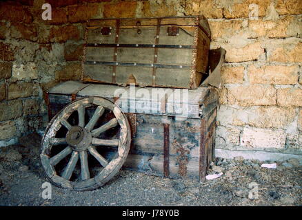 Old wooden chests stand one on one and the wheel is on them Stock Photo