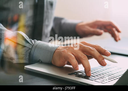 close up of businessman working with mobile phone and stylus pen and laptop computer  on wooden desk in modern office Stock Photo