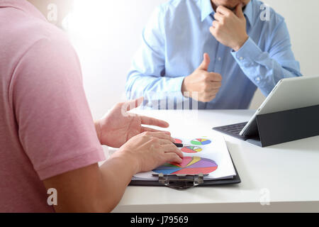 Businessmen working together on a document and using smart phone and digital tablet and laptop computer in modern office Stock Photo