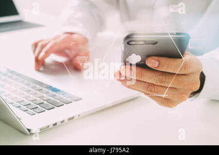 close up of businessman using mobile phone and laptop computer on white desk in modern office with VR icons diagram Stock Photo