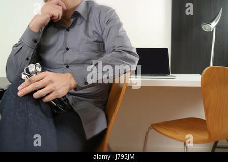 smart medical doctor holding stethoscope and thinking with laptop computer on dark wooden desk in modern office Stock Photo