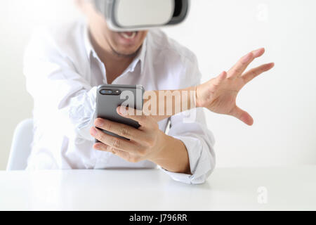 businessman wearing virtual reality goggles in modern office with Smartphone using with VR headset Stock Photo