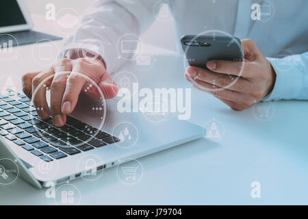 Big data analytics with business intelligence (BI) concept. businessman using mobile phone and laptop computer on white desk with VR chart and graph w Stock Photo