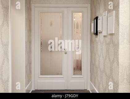 Interior of a modern and new hotel, details of reception room, bright entrance doors with some picture frames and decorative wallpapers. Stock Photo