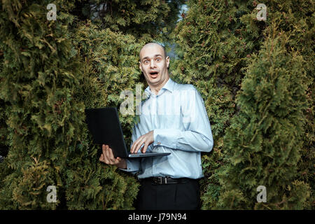Man with a laptop in the hands of very frightened screams. Stock Photo